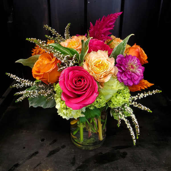 Bright mixed bouquet of roses and zinnias in a glass vase