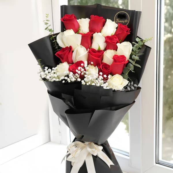 Bouquet of red and white roses wrapped in black paper with a white ribbon