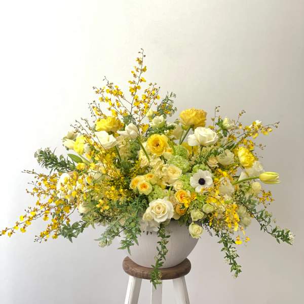 Large yellow and white floral arrangement in a white vase