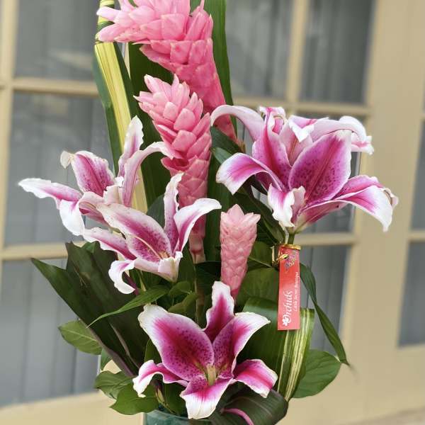 Pink lilies and tropical blooms in a glass vase