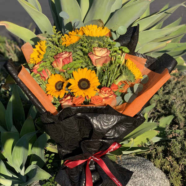 Bouquet of orange sunflowers and roses wrapped in black paper