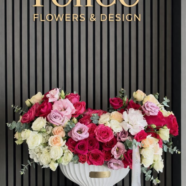 Large rose arrangement in a white pedestal vase