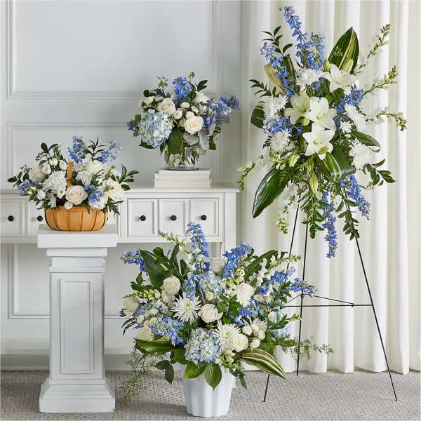 Blue and white floral arrangements in vases and a basket on stands
