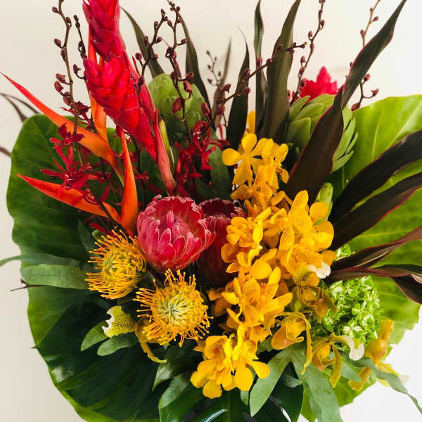 Tropical bouquet with red and yellow flowers in a black vase