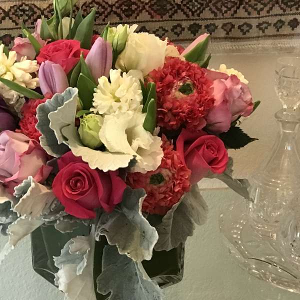 Mixed bouquet of roses, tulips, and carnations in a glass vase