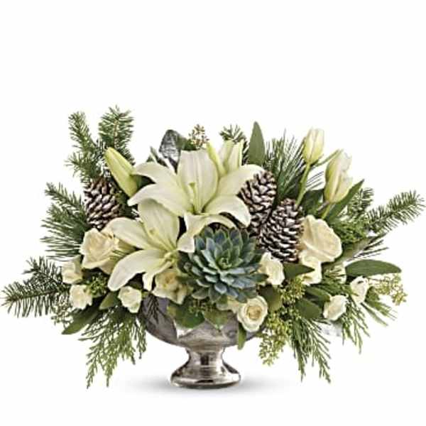 White lilies and pinecones arranged in a silver pedestal bowl