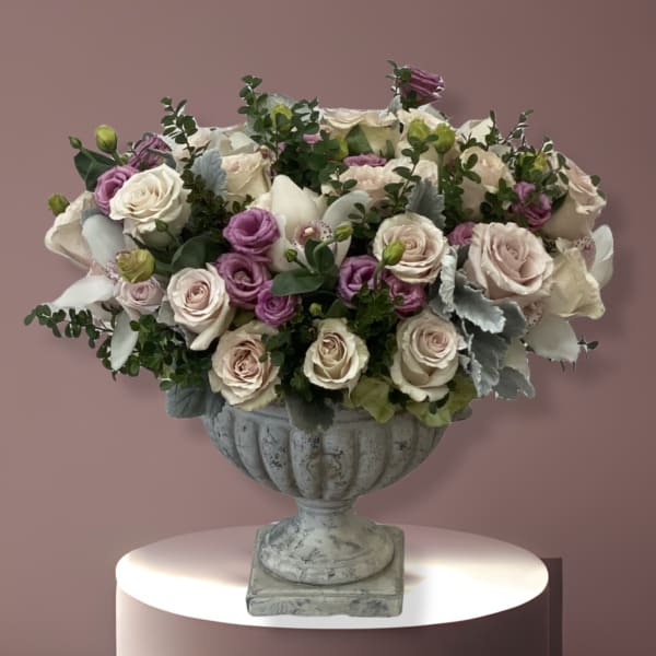 Pink and white roses arranged in a gray urn vase