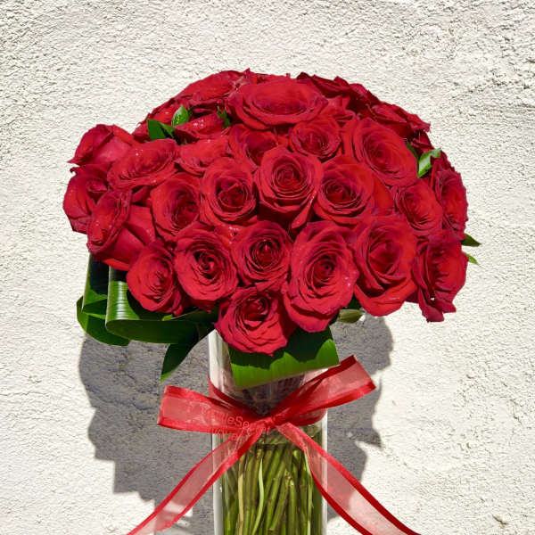 Bouquet of red roses in a clear glass vase with a red ribbon