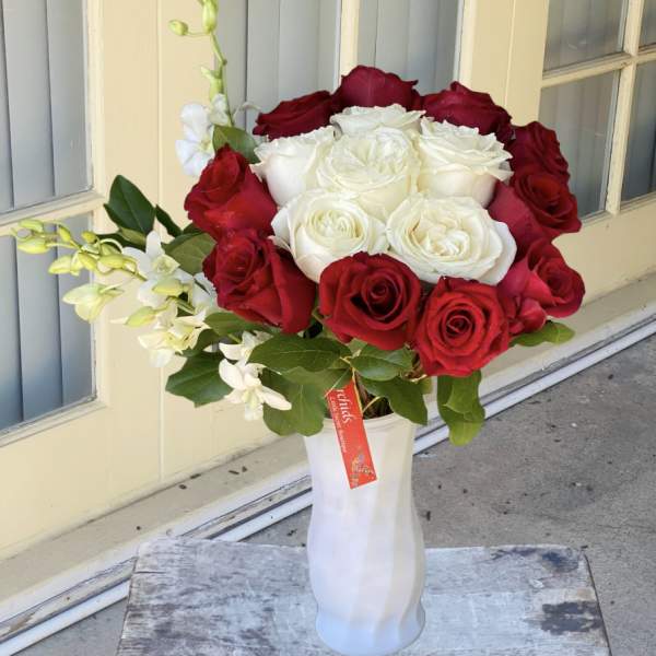 Red and white roses arranged in a white vase