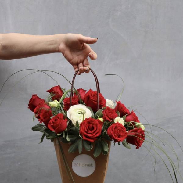 Red and white roses arranged in a brown handled gift bag