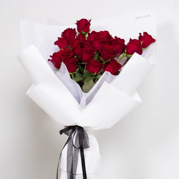 Bouquet of red roses wrapped in white paper with a black ribbon