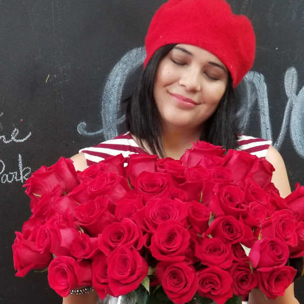 Woman holding a large bouquet of red roses in a glass vase