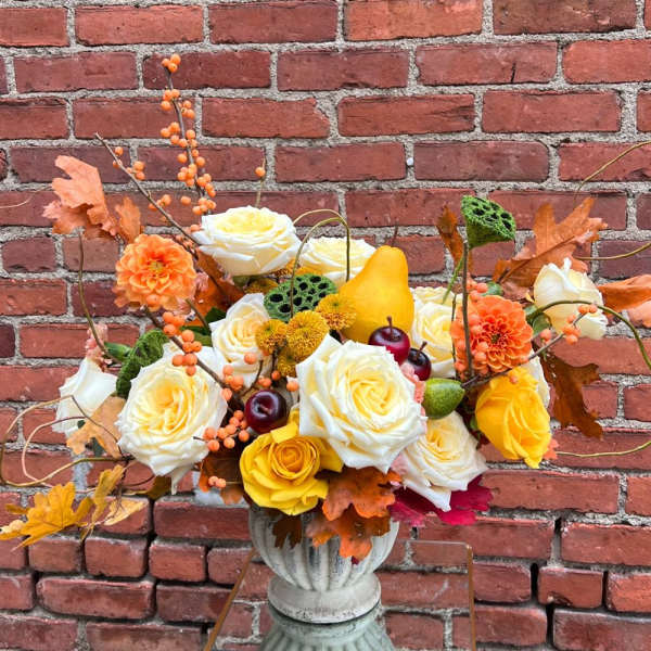 Autumn floral arrangement with roses, dahlias, and berries in a pedestal vase