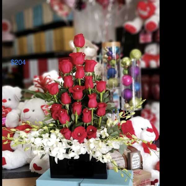 Red roses arranged in a black box with white orchids at the base