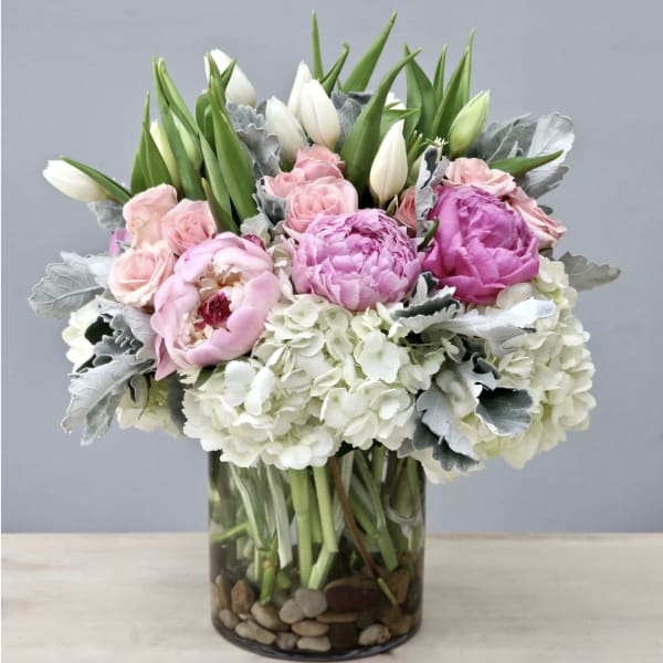 Pink and white bouquet in a glass vase with peonies, roses, and hydrangeas