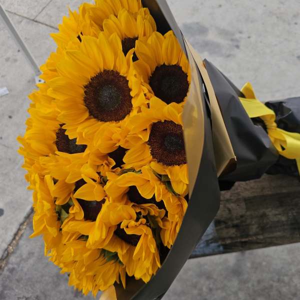 Bouquet of yellow sunflowers wrapped in black paper with a yellow ribbon