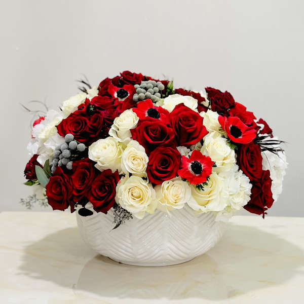Red and white rose arrangement in a white ceramic bowl