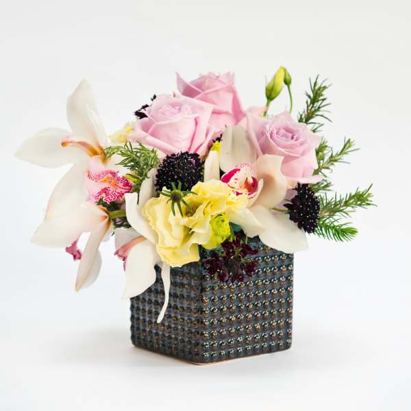 Pink roses and white orchids in a textured square vase