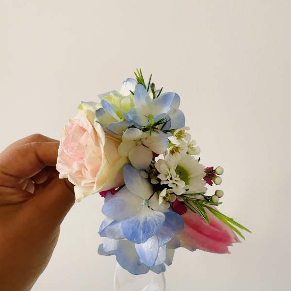 Handheld corsage with a pale pink rose and blue-white flowers