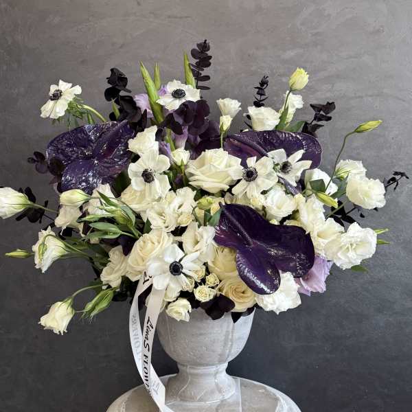 White and purple floral arrangement in a gray urn vase