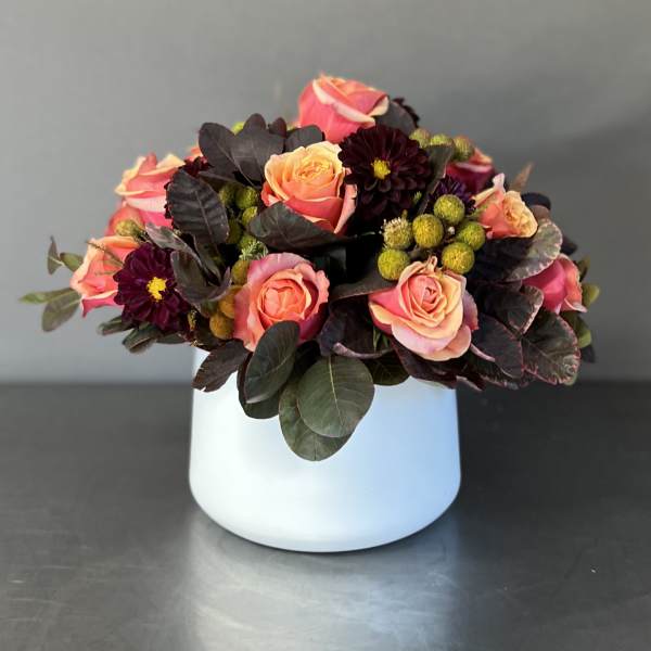 Pink and peach roses arranged in a white vase