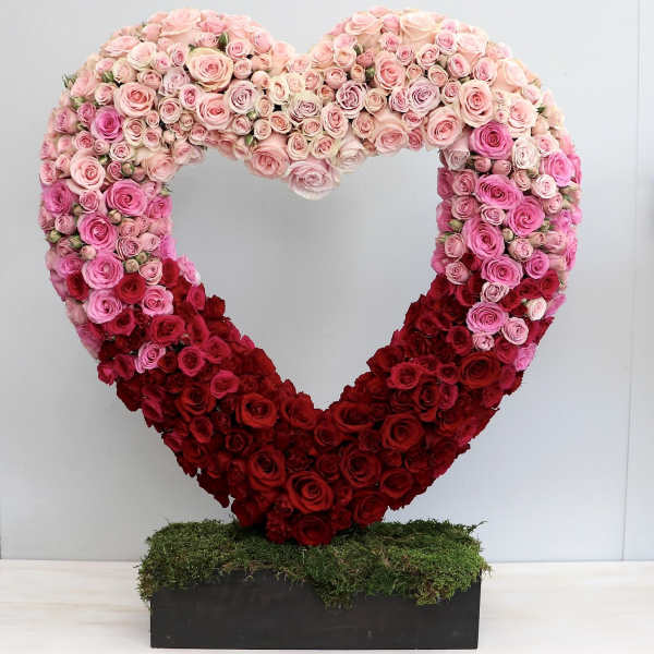 Large open heart of pink and red roses on a moss-covered rectangular base