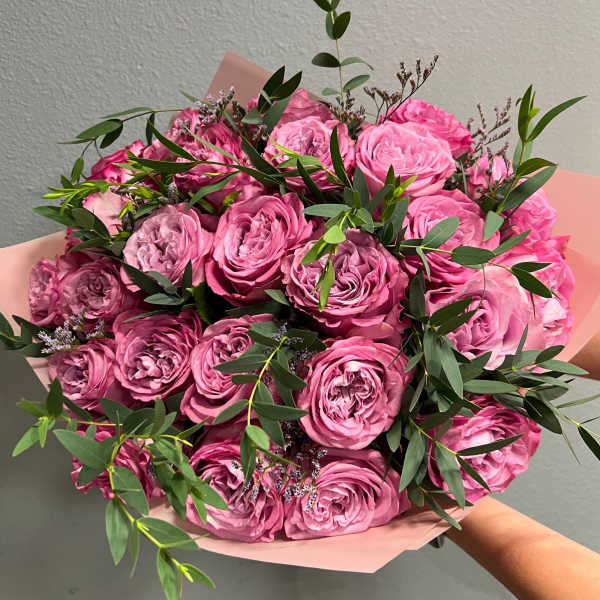 Bouquet of pink roses with green foliage in pink wrapping