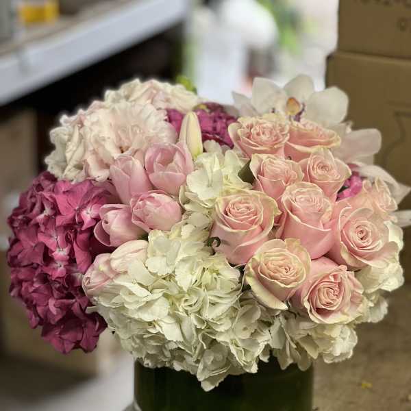 Pink roses and hydrangeas arranged in a green glass vase