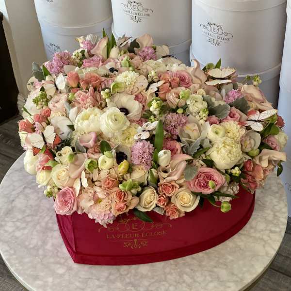 Large pastel flower arrangement in a red hat box