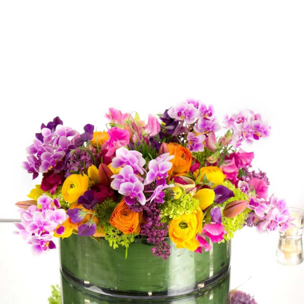 Colorful bouquet of orchids and ranunculus in a glass vase