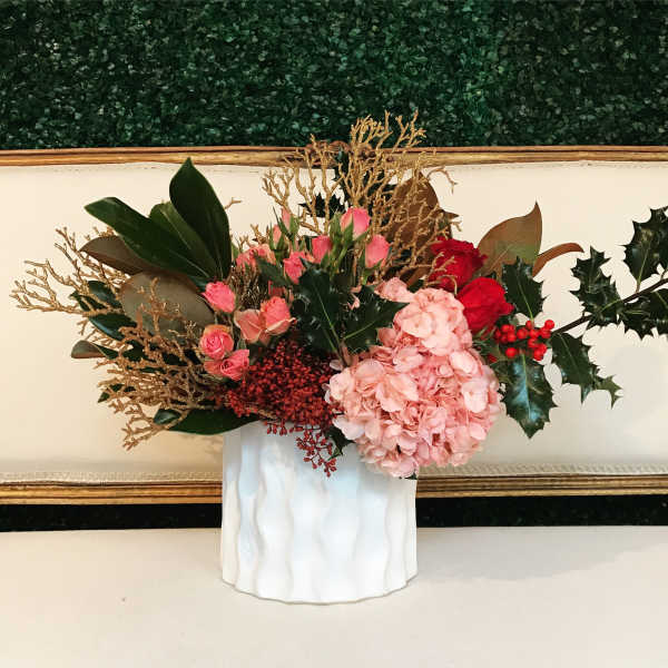 Pink flowers and red berries arranged in a white vase with gold branches