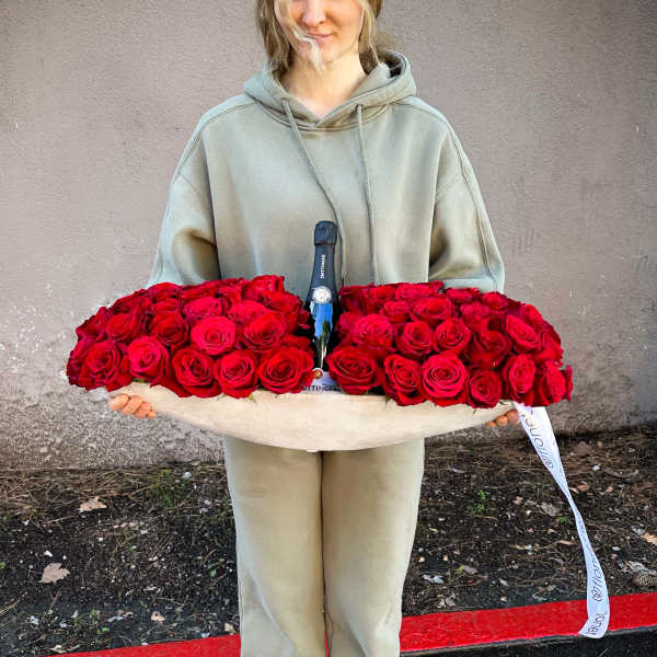 Woman holding a large tray of red roses with a champagne bottle in the center
