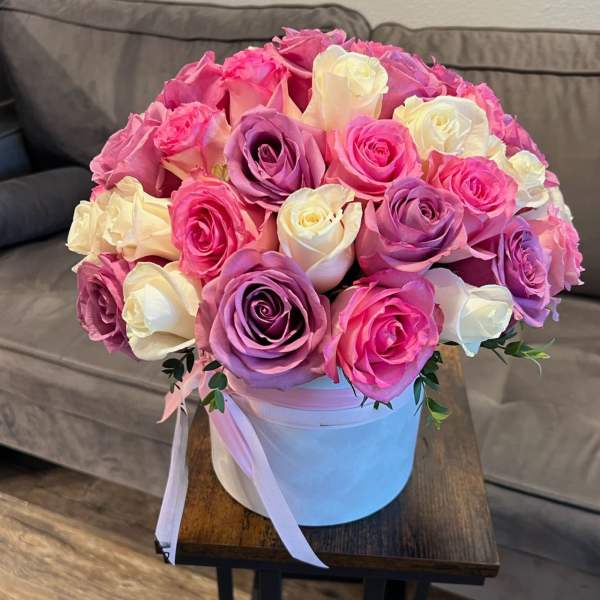 Bouquet of pink, purple, and white roses in a white hat box