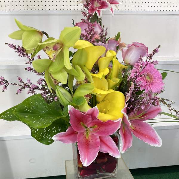 Mixed bouquet of pink and yellow flowers in a clear glass vase