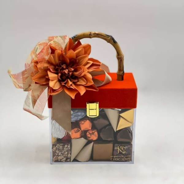Gift box of assorted chocolates topped with an orange flower and ribbon