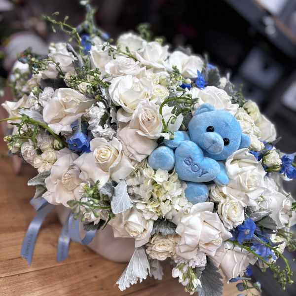 White rose bouquet with a blue teddy bear in the center