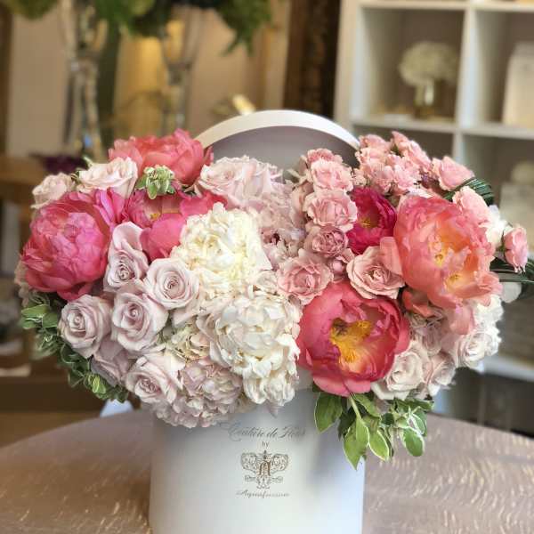Pink and white floral arrangement in a white hatbox