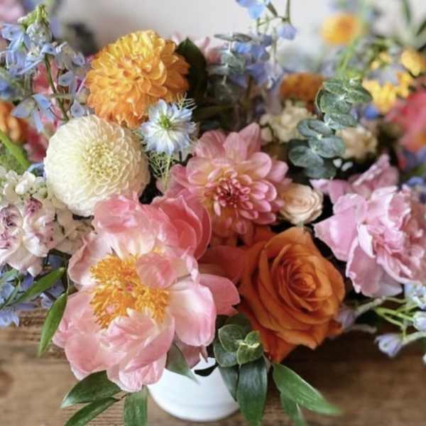 Mixed bouquet of pink, orange, and white flowers in a white vase