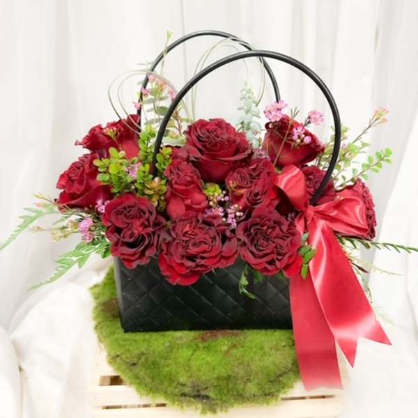 Red roses in a black basket with a pink ribbon