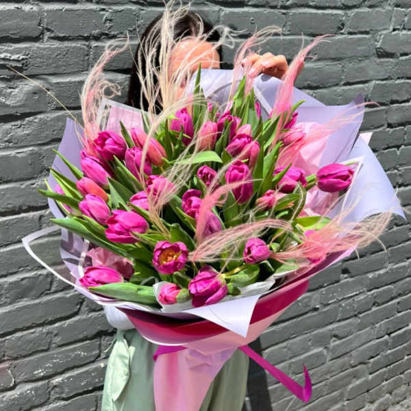 Bouquet of bright pink tulips wrapped in pastel paper