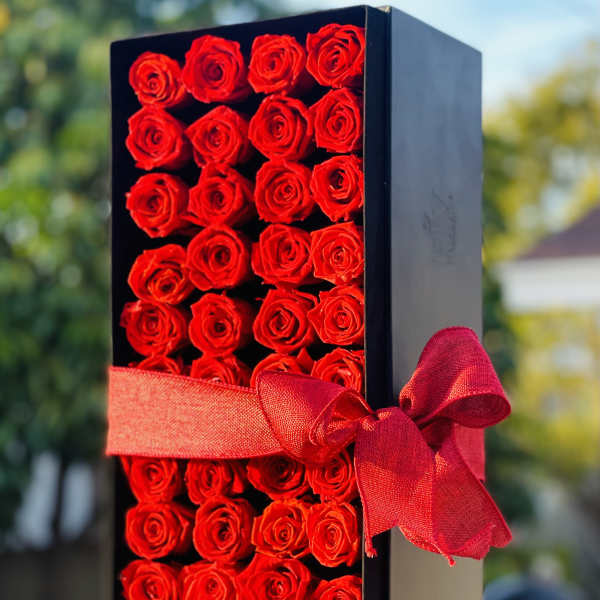 Black box filled with red roses and tied with a red ribbon