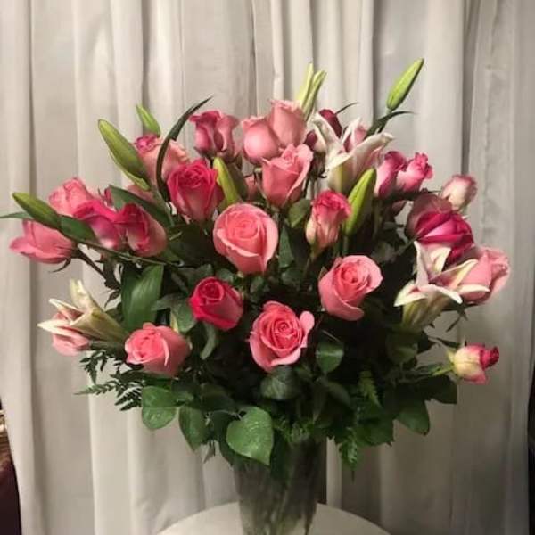 Pink roses and lilies arranged in a clear glass vase