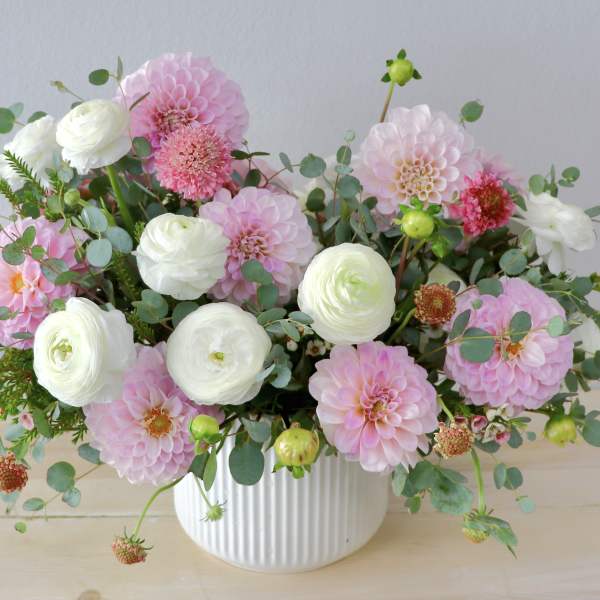 Pink and white flowers arranged in a white ribbed vase