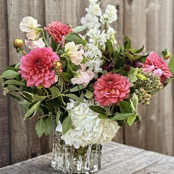 Pink and white flowers arranged in a clear glass vase