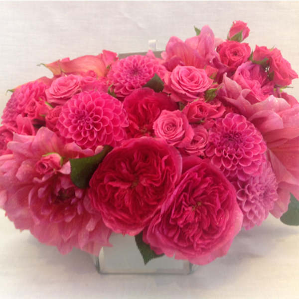 Pink bouquet of roses and dahlias in a clear square vase