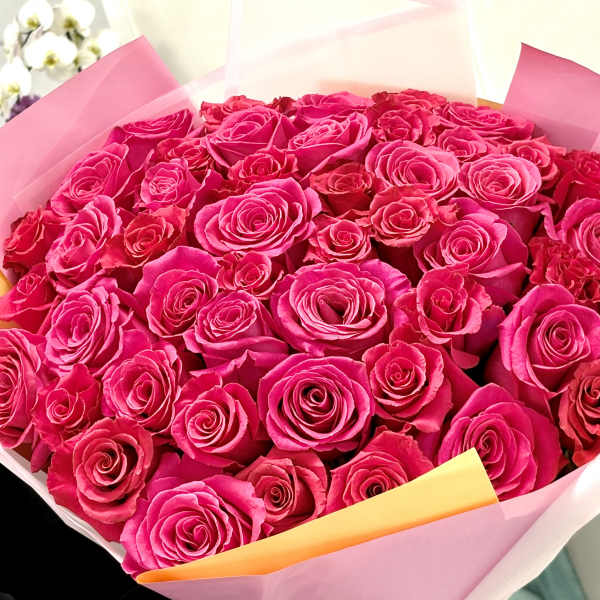 Bouquet of bright pink roses wrapped in pink paper