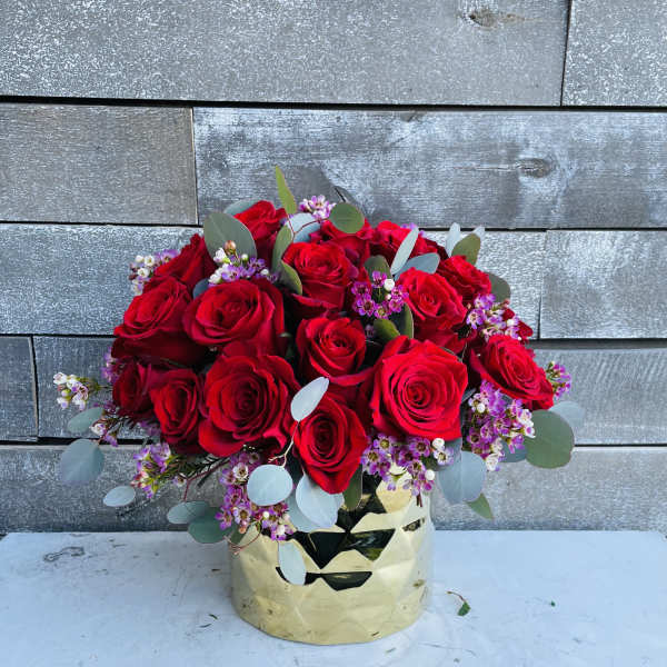 Bouquet of red roses with small purple filler flowers in a gold vase