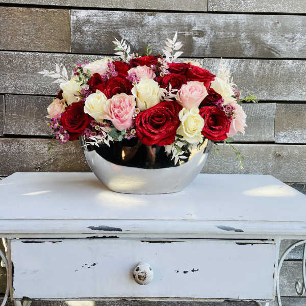 Red, pink, and white roses arranged in a silver bowl
