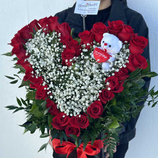 Heart-shaped bouquet of red roses with baby's breath and a teddy bear
