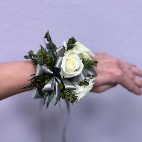 White rose wrist corsage with silver ribbon and greenery